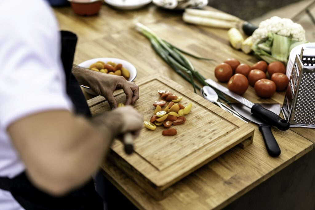 Hände schneiden Gemüse auf einem Brett – Meal Prep für Abnehmen ohne Sport