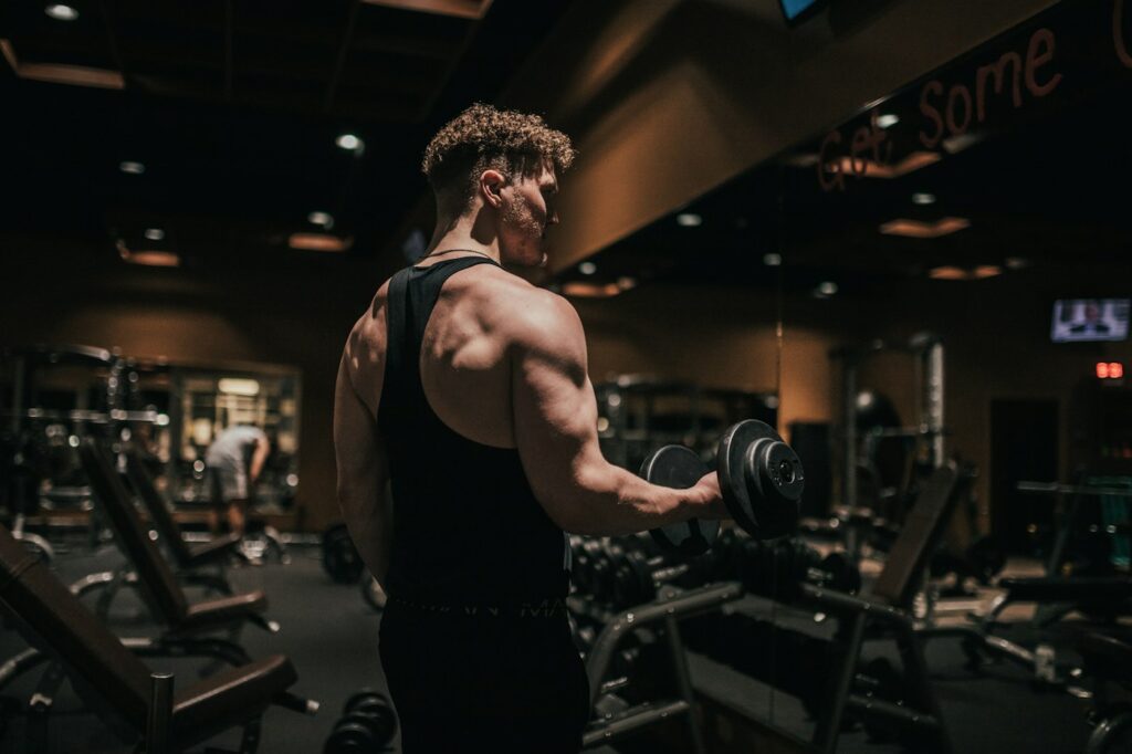 Mann hält Kurzhantel im Fitnessstudio für Bizeps Übungen bereit