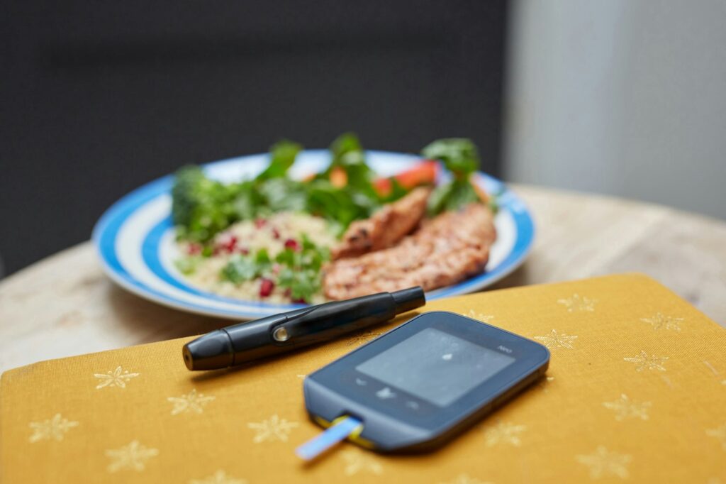 Teller mit Essen neben Messgerät, Werte werden in die Blutzucker Tabelle eingetragen