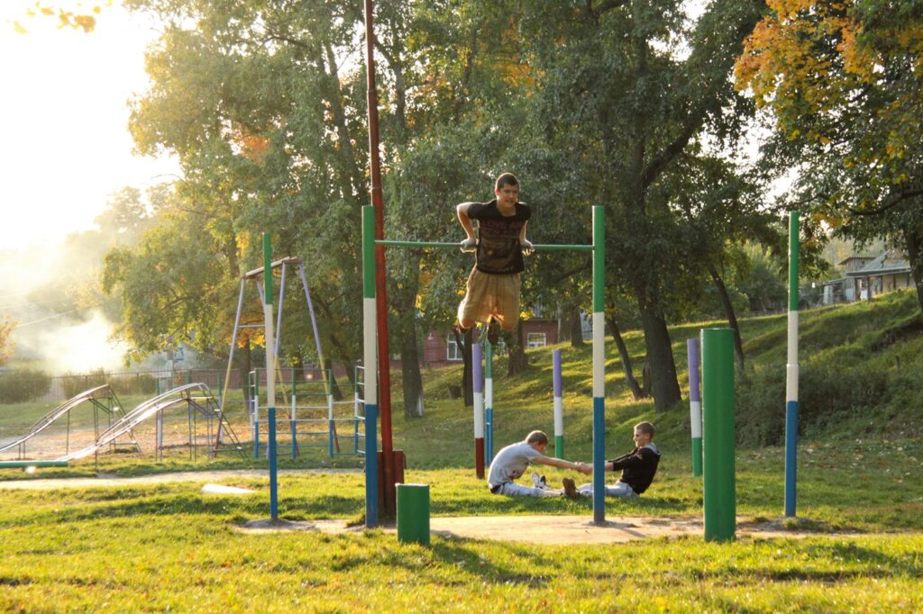 Menschen trainieren im Outdoor-Fitnesspark mit Stangen für Calisthenics Übungen