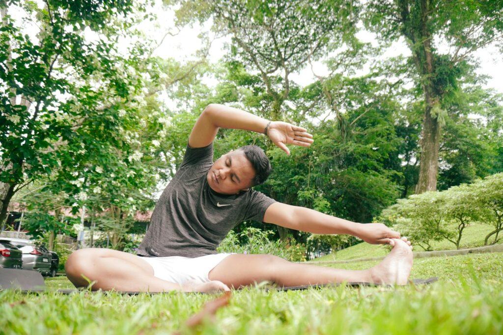 Mann auf einer Yogamatte im Park beim ruhigen Dehnen nach dem Sport