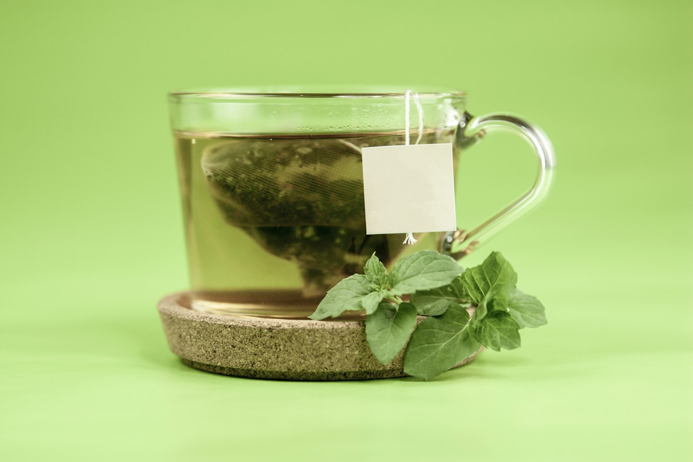 Glasbecher mit frischen Teeblättern zur Frage, ob grüner Tee gesund ist