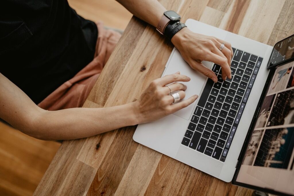 Hände tippen auf Laptop, häufiger Auslöser für Handgelenk Schmerzen