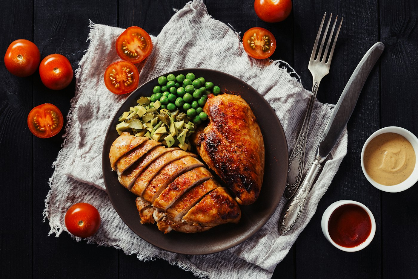 Geschnittene Hähnchenbrust mit Erbsen auf dunklem Teller für High Protein Rezepte