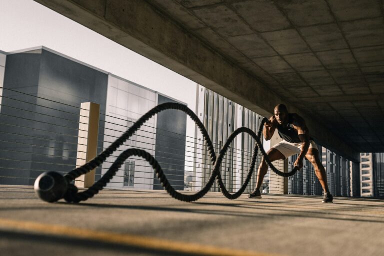 HIIT Training: Mann trainiert draußen intensiv mit schweren Battle Ropes
