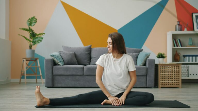 Frau auf der Yogamatte im Wohnzimmer beim Hüfte dehnen