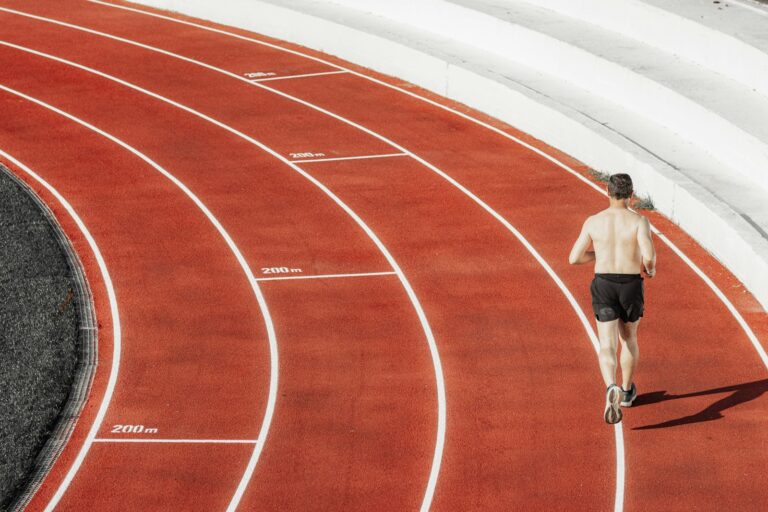 Intervalltraining Laufen: Läufer sprintet auf einer roten Tartanbahn mit weißen Linien