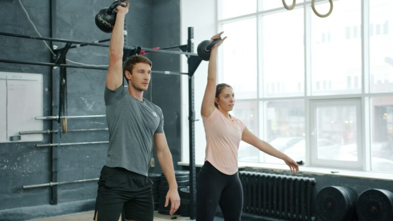 Kettlebell Training: Mann und Frau führen im Fitnessstudio gemeinsam Kettlebell-Swings aus