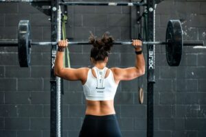 Krafttraining für Anfänger: Frau trainiert im Fitnessstudio mit Gewichten beim Krafttraining