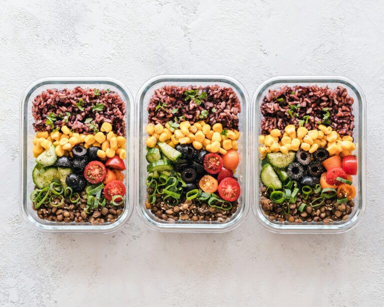 Meal Prep: Glasbehälter mit Reis, Mais, Oliven, Tomaten, Gurken und Linsen fürs Meal-Prep