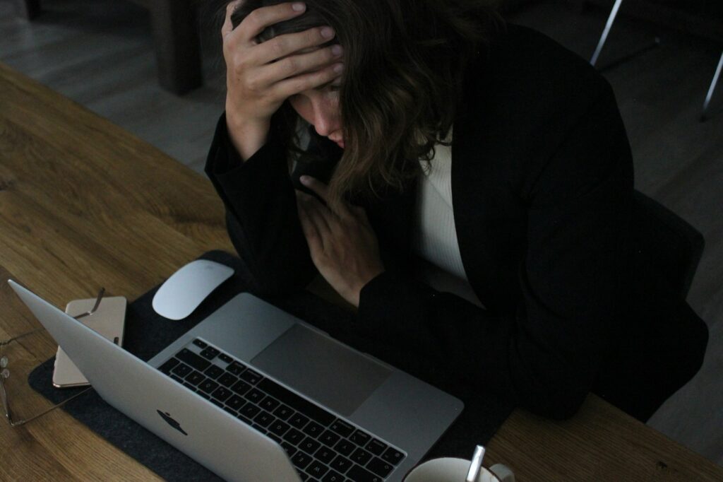 Erschöpfte Frau stützt den Kopf am Laptop wegen Müdigkeit trotz viel Schlaf