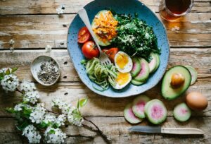 Proteinreiches Frühstück: Pochiertes Ei mit frischem Gemüse und Tomaten auf blauem Teller