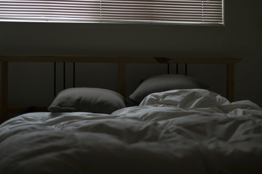 Aufgeräumtes helles Bett als ruhige Umgebung für erholsamen REM-Schlaf