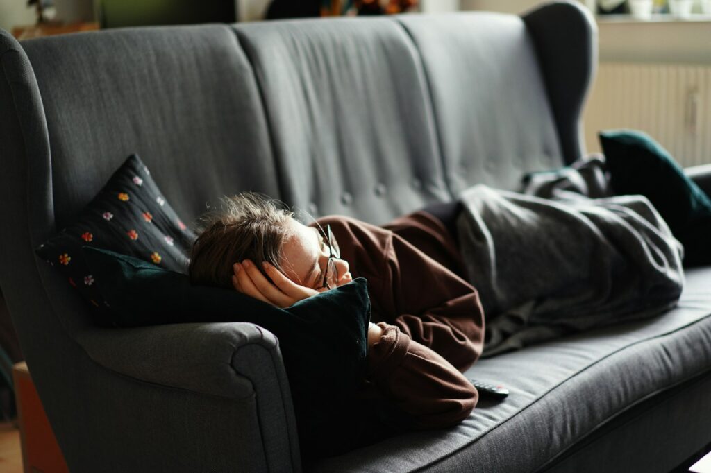 Frau liegt am Tag auf dem Sofa und will Schlaf nachholen