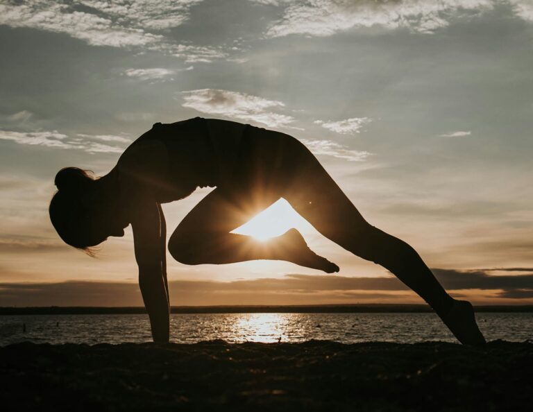 Frau übt Sonnengruß Yoga mit erhobenen Armen vor der Sonne
