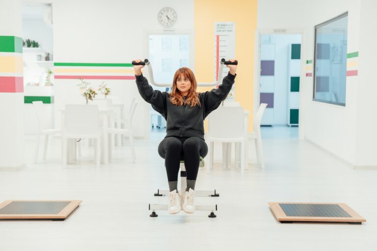 Frau sitzt auf einem Stuhl und streckt beim Stuhl Yoga die Arme nach oben