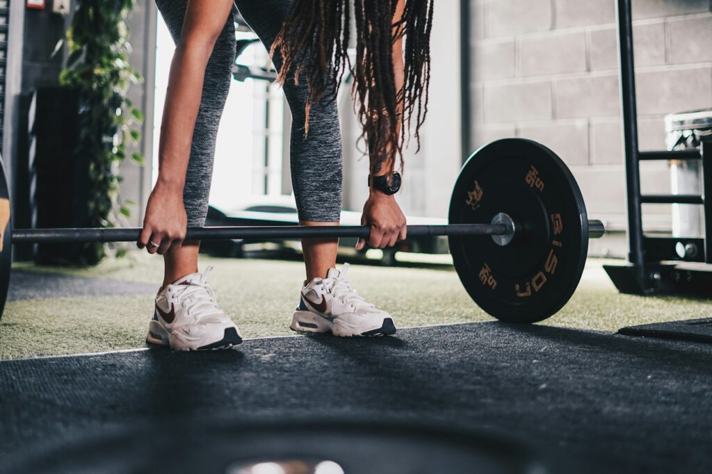 Frau hebt eine Langhantel im Fitnessstudio nach ihrem Trainingsplan Muskelaufbau