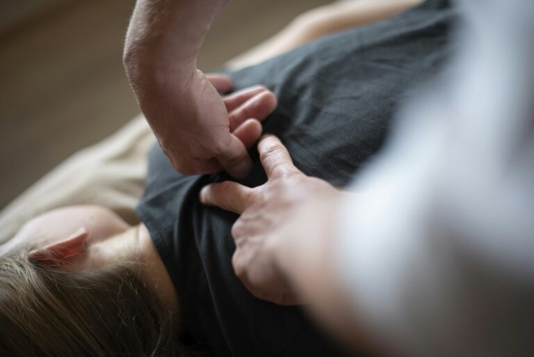 Hände massieren den Rücken einer Person, die verklebte Faszien vermutet