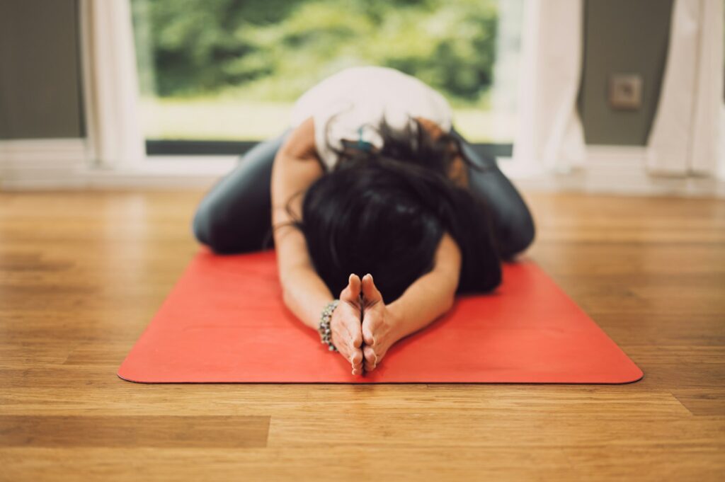 Frau liegt entspannt auf einer Matte zum Abschluss der Yin Yoga Praxis