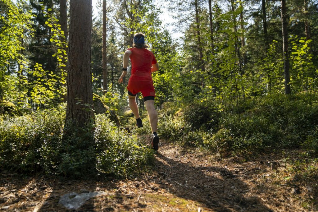 Läufer im roten Shirt beim Zone 2 Laufen durch den Wald