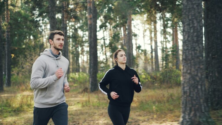 Paar beim ruhigen Zone 2 Laufen auf einem Waldweg