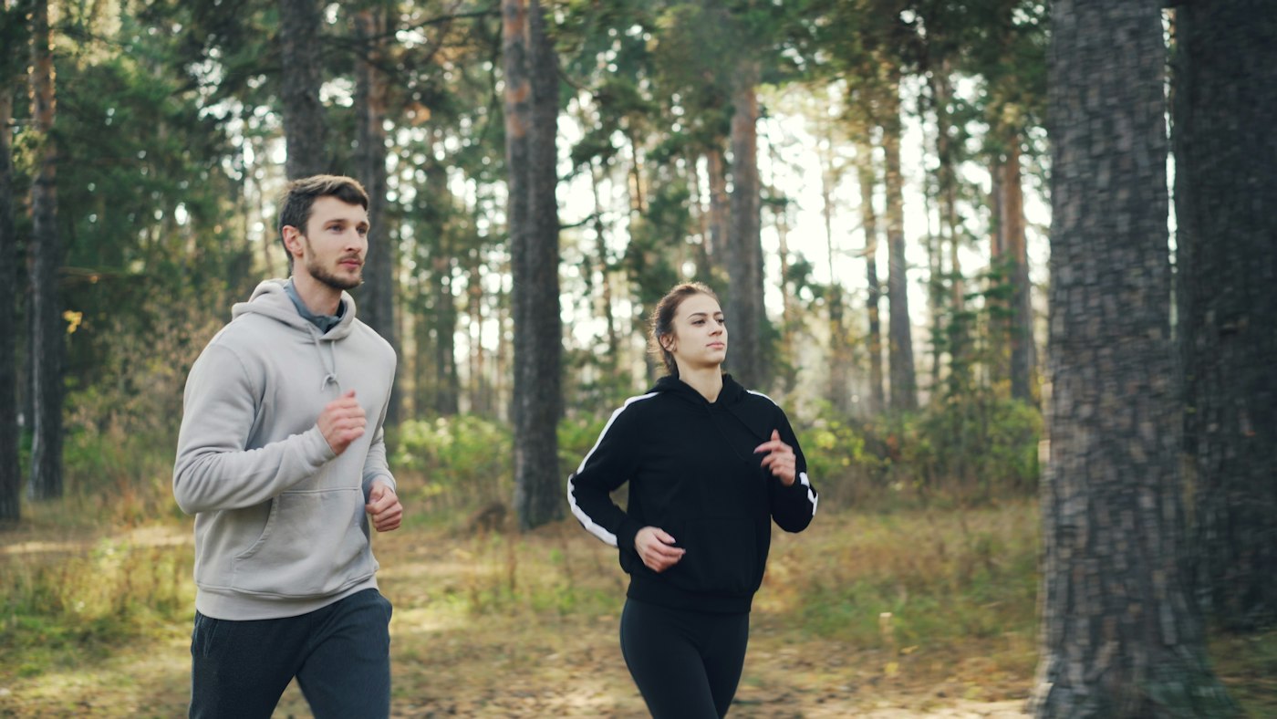 Paar beim ruhigen Zone 2 Laufen auf einem Waldweg